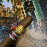 Cigar with a label held in front of a painting of 'The Cigar Room'. El Rey del Mundo W.I.H. 20 Years Regional Edition Lebanon 