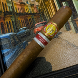 Cigar with a visible label on a textured surface, with a colorful cityscape in the background. El Rey del Mundo W.I.H. 20 Years Regional Edition Lebanon 