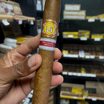 Cigar held by a hand with a blurred store shelf in the background. El Rey del Mundo W.I.H. 20 Years Regional Edition Lebanon 