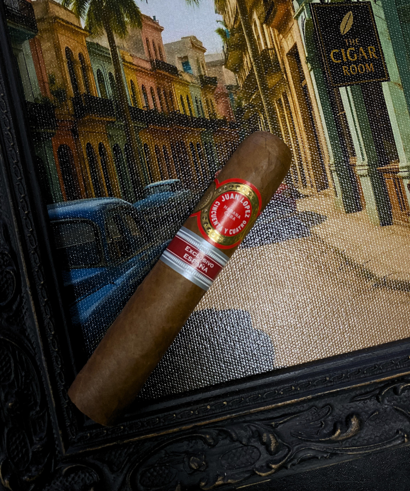 Cigar with a brand label on a textured surface, with a cityscape in the background. Juan Lopez Cincuenta y Cuatro Regional Edition Spain 2025 