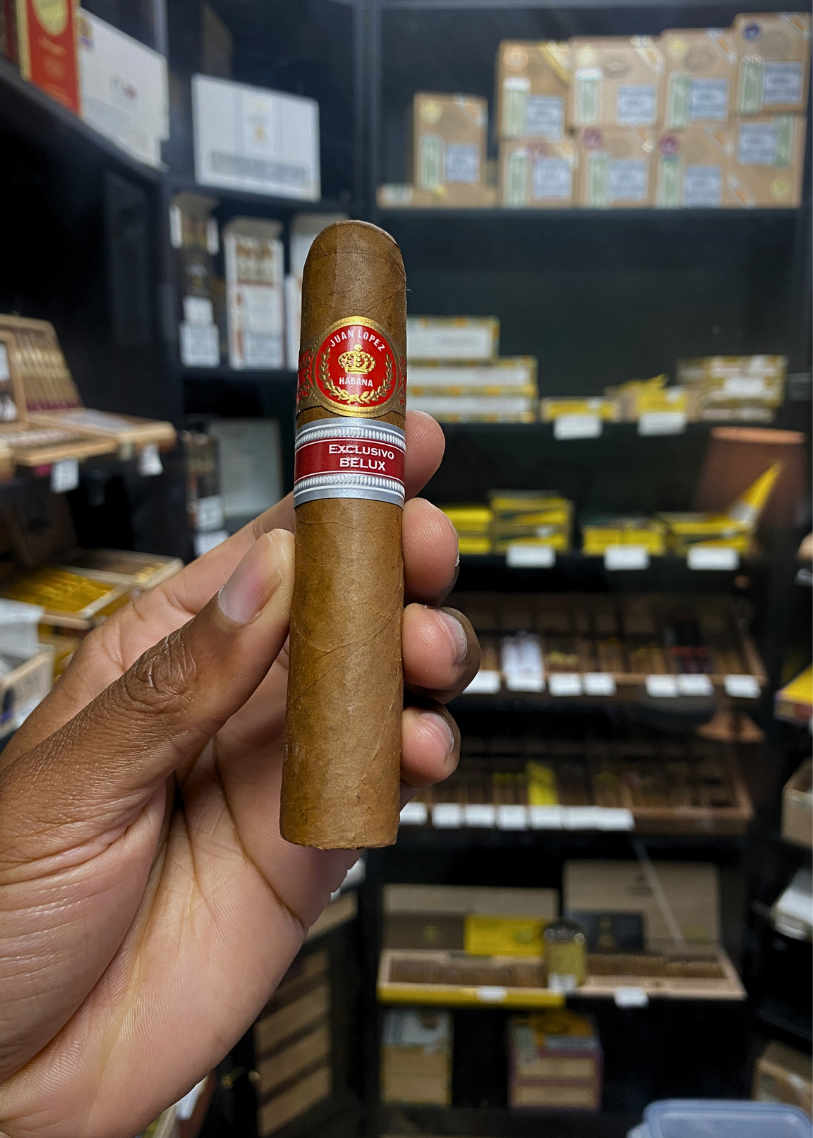 Hand holding a cigar with a brand label in a store setting