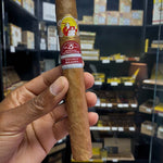 Cigar held by a hand with a blurred store shelf in the background