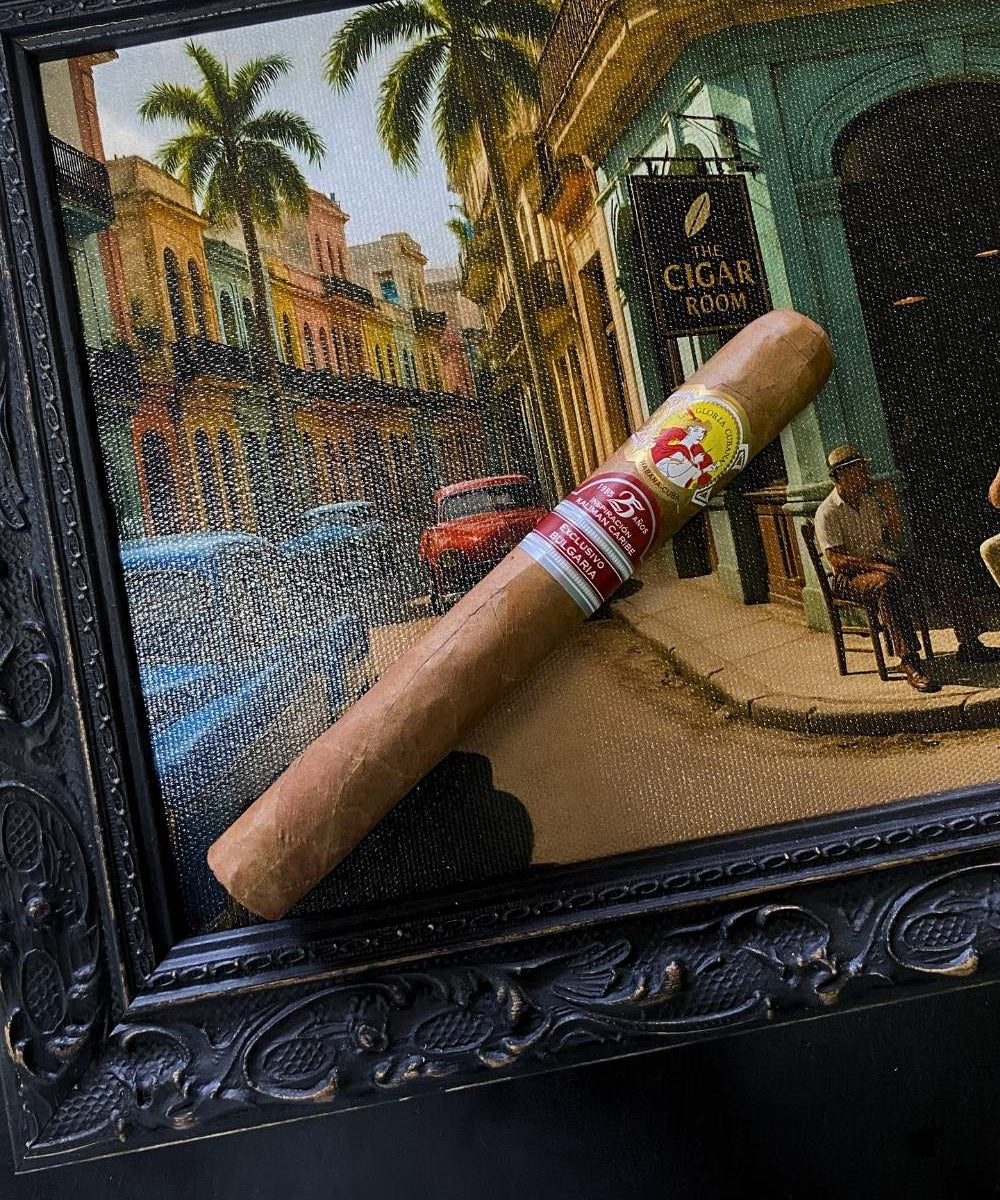 Cigar with a 'Vitello' label in front of a framed painting of a street scene.
