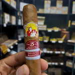 Cigar with a visible label held in front of a shelf with more cigars.