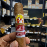 Cigar with a visible label held in front of a shelf with more cigars.