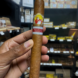 Cigar held by a hand with a blurred store shelf in the background