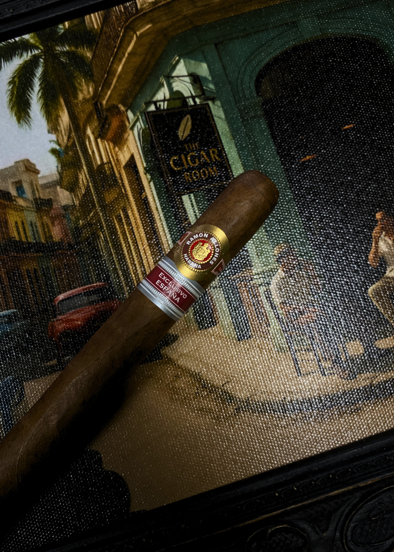 Cigar with a band in front of a mosaic wall featuring a cigar store sign. Ramón Allones Grandes Regional Edition Spain