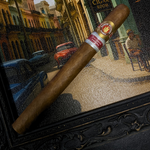 Cigar with a brand label on a decorative frame, set against a city street scene. Ramón Allones Grandes Regional Edition Spain