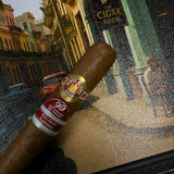 Cigar with a brand label on a decorative surface featuring a painting of a street scene. Ramón Allones Sr. Henry Regional Edition Germany 2020 