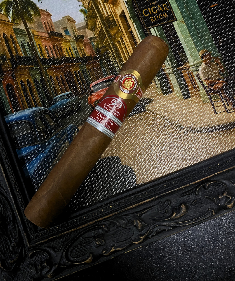 Cigar with a brand label in front of a painting of a city street scene. Ramón Allones Sr. Henry Regional Edition Germany 2020 