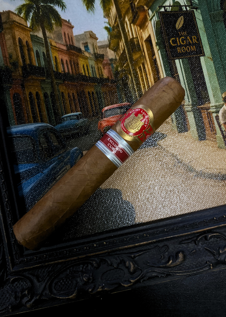 Cigar with a brand label on a decorative surface, with a cityscape in the background.Saint Luis Rey Marquéz Regional Edition Exclusive Cuba 2016