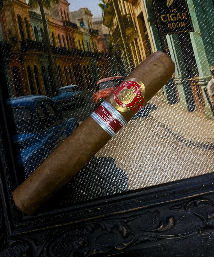 Cigar with a brand label on a decorative surface, with a cityscape in the background.Saint Luis Rey Marquéz Regional Edition Exclusive Cuba 2016