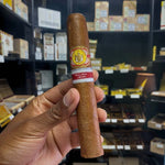 Cigar held in a hand with a blurred background of shelves with cigars